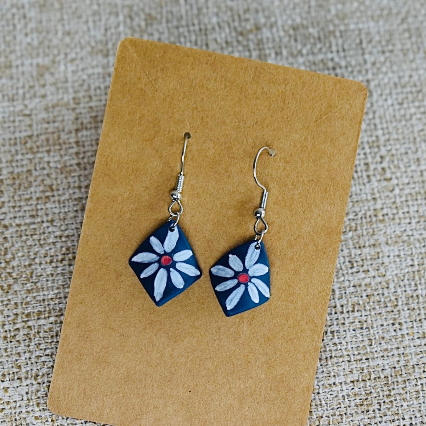Handmade polymer clay earrings featuring a blue and white daisy design